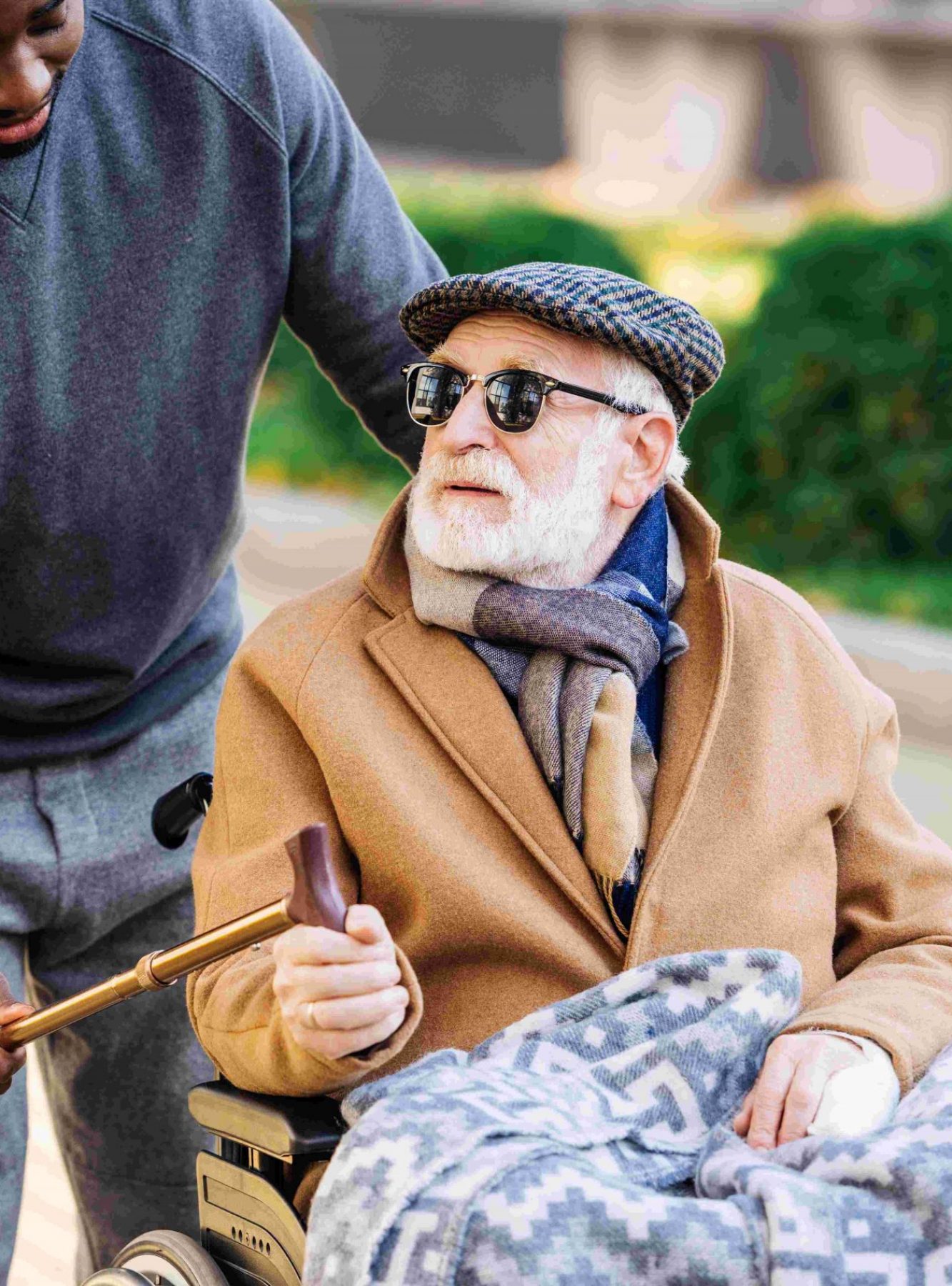 young african american man giving walking stick to senior disabled man in wheelchair on street